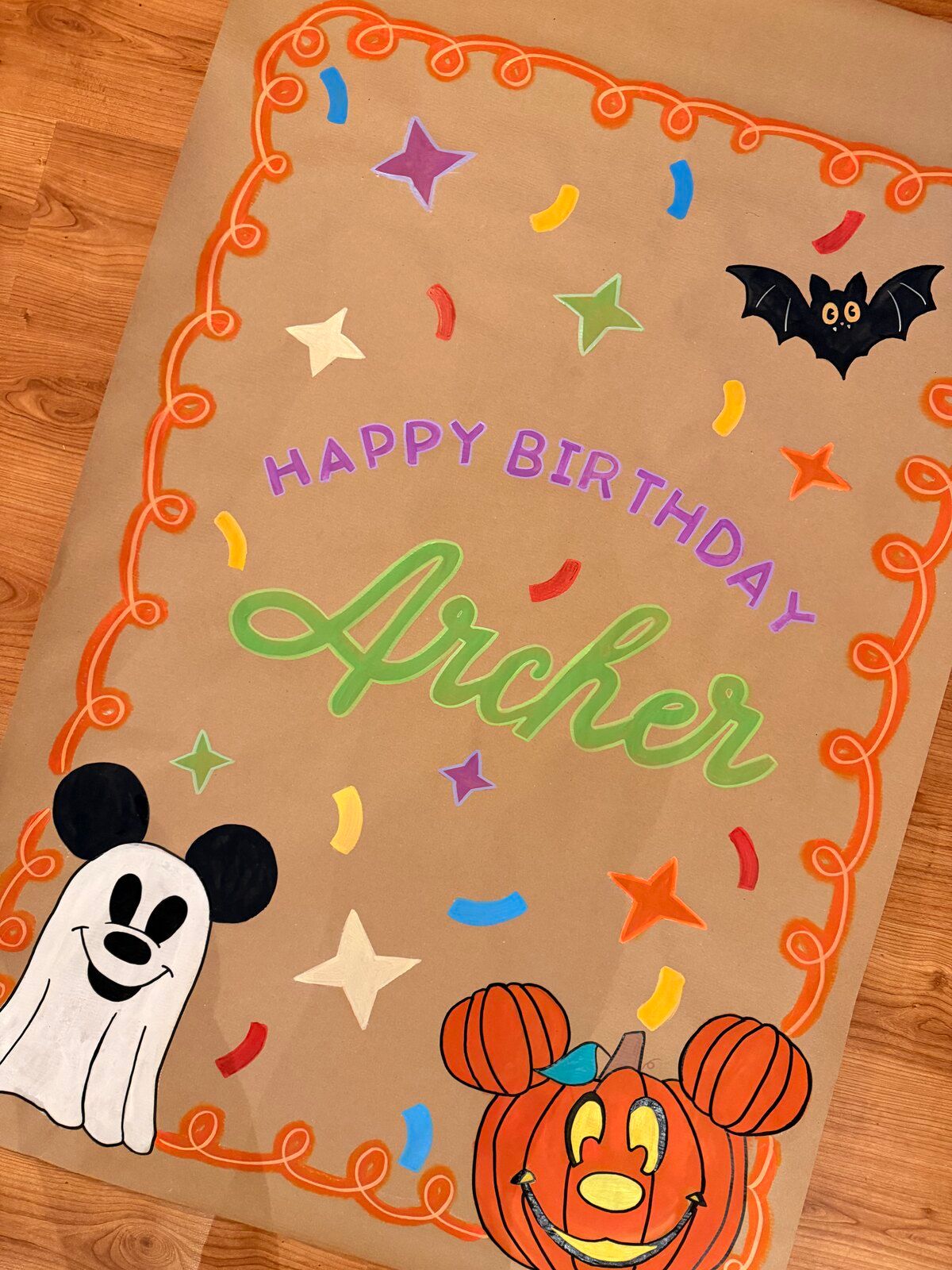 The “Happy Birthday Archer” Halloween banner laid on a wooden floor, seen at an angle.