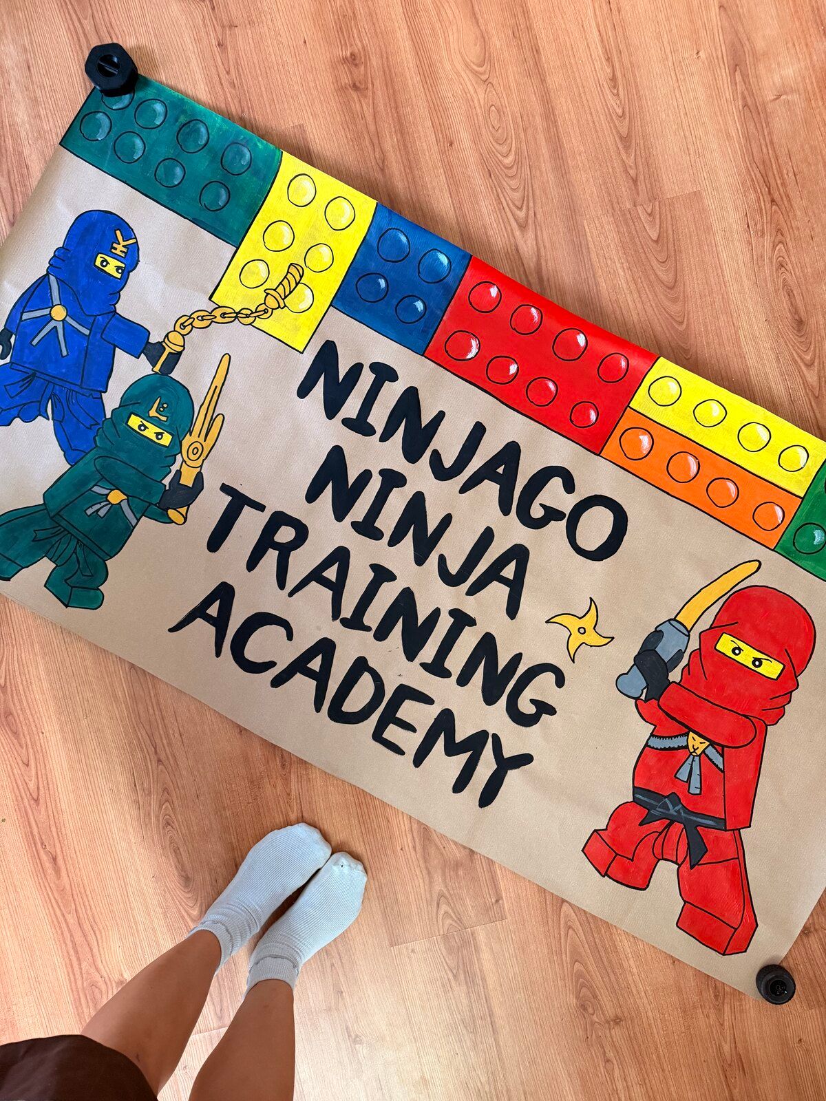 The “Ninjago Ninja Training Academy” banner on a wooden floor, seen from the other end.