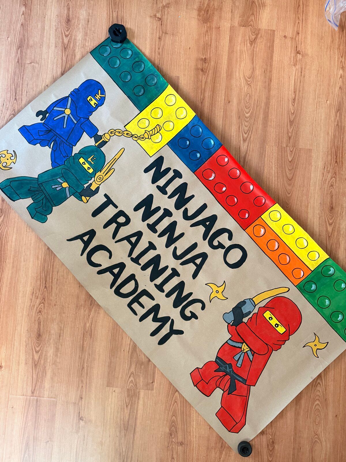 The “Ninjago Ninja Training Academy” banner laid diagonally on a wooden floor.