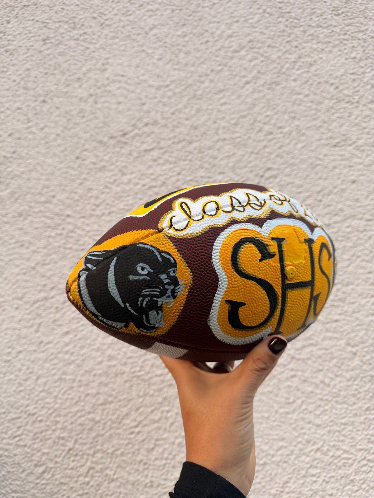 The painted football turned to show a black panther’s head on gold and the letters “SHS”.