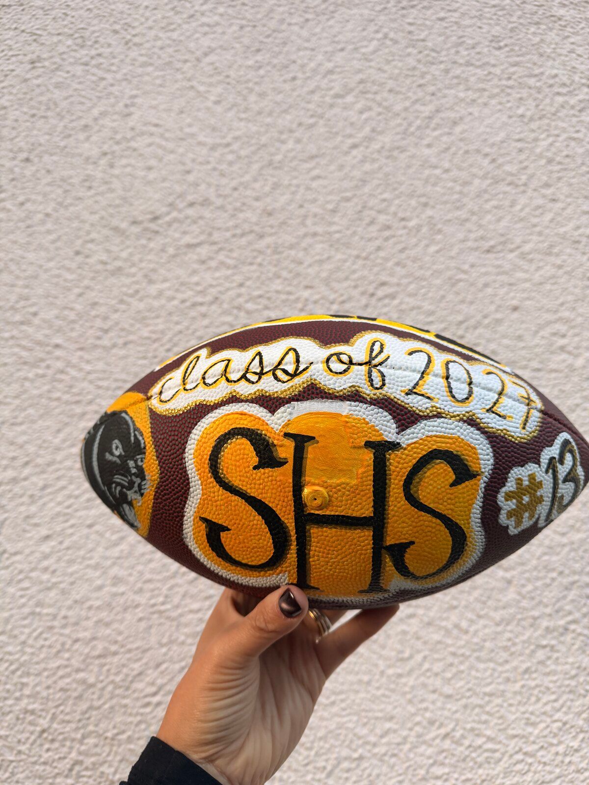 The painted football showing “class of 2027”, “SHS” on a gold panel and “#13”.
