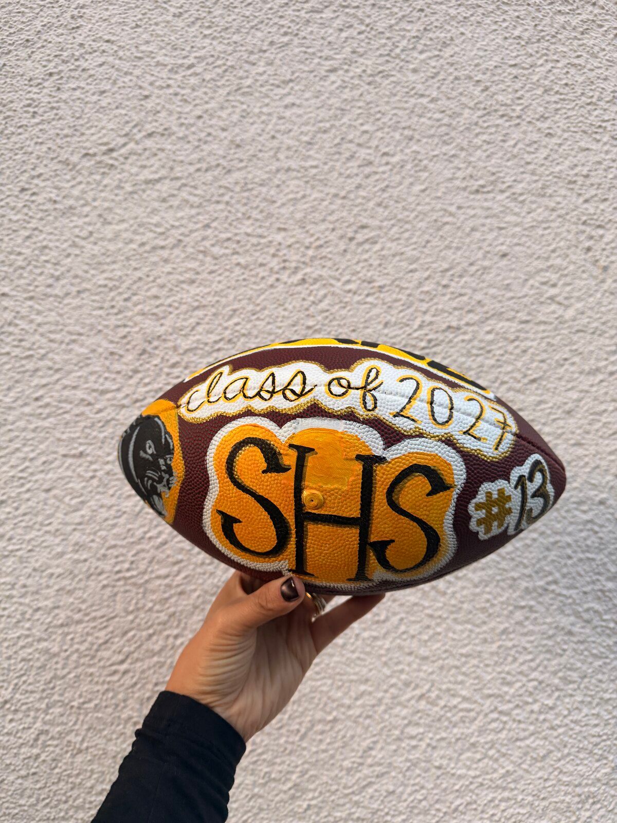 The painted football from the side, with “SHS”, “#13” and the edge of the panther.